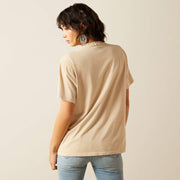 Woman wearing a beige t-shirt and light blue jeans against a plain background
